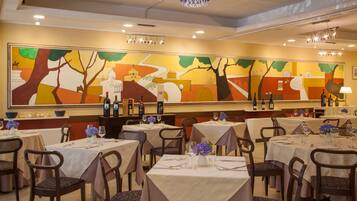 Un ristorante con diversi tavoli e sedie, ognuno apparecchiato con tovaglie bianche e fiori blu.
