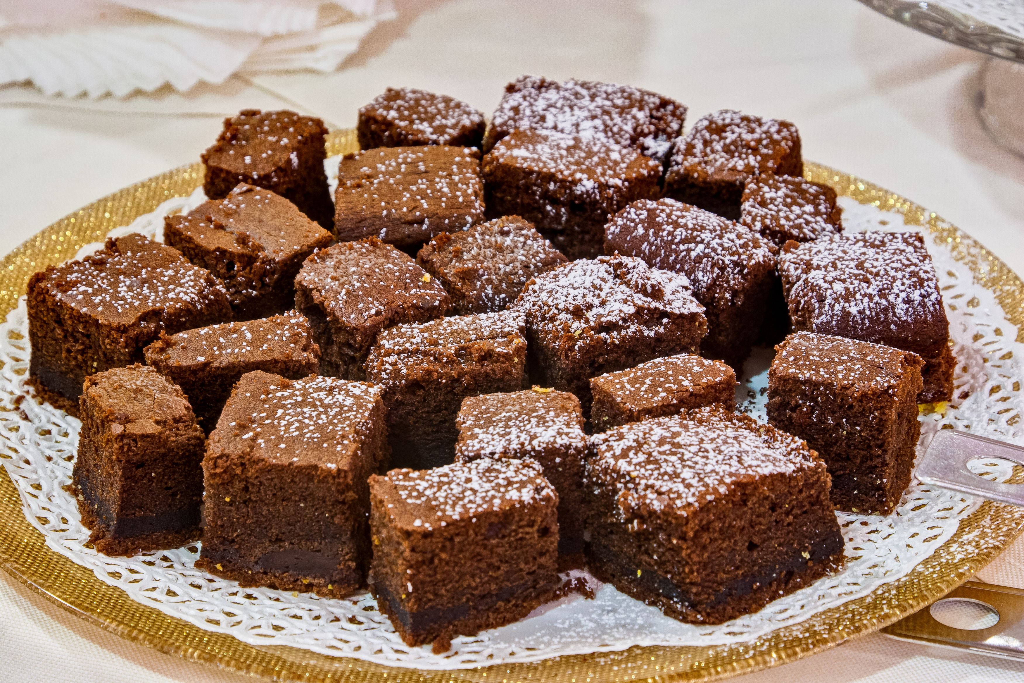 Eine Platte mit Brownies auf einer goldenen, weißen Spitzendecke.