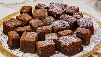 Eine Platte mit Brownies auf einer goldenen, weißen Spitzendecke.