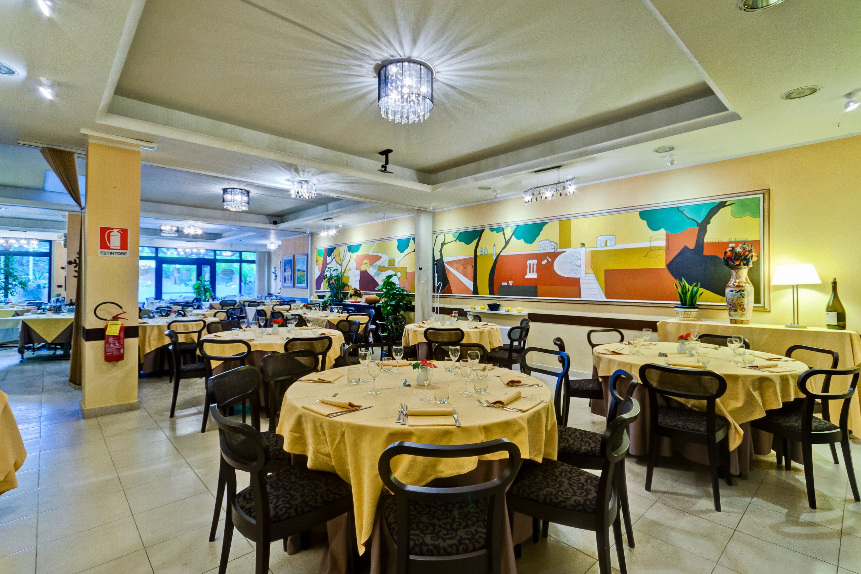 Ein Restaurant mit runden Tischen, Stühlen und einer Chandelüster.
