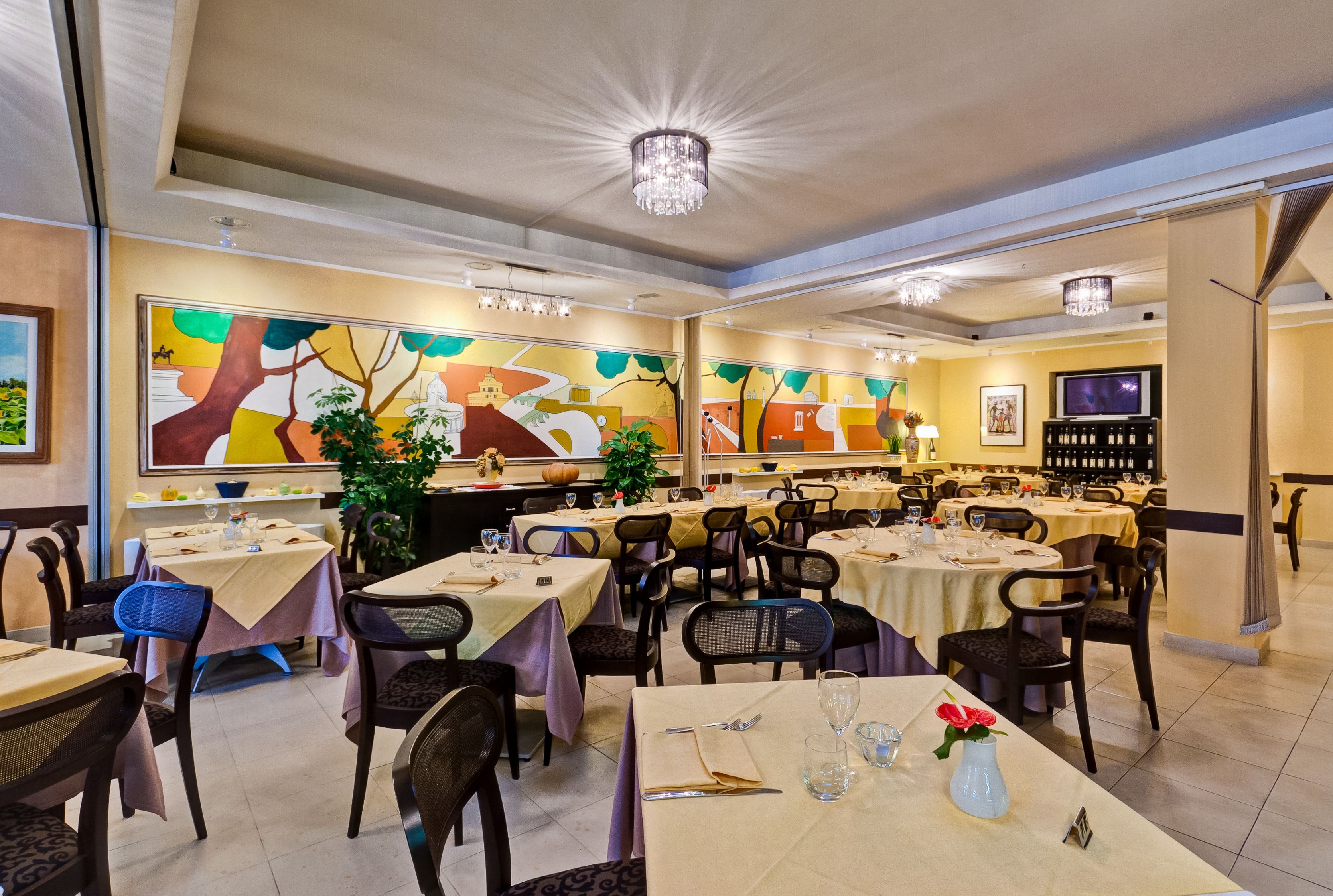 A restaurant with multiple tables, chairs, and a chandelier.
