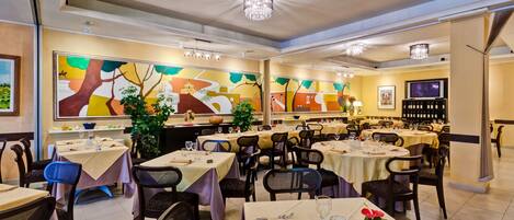 A restaurant with multiple tables, chairs, and a chandelier.