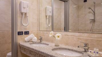 Un baño con dos lavamanos, un espejo, un perchero para toallas y una ducha.