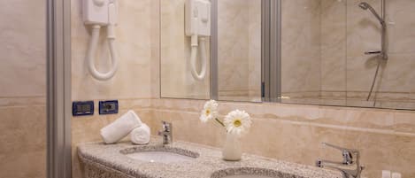 Een badkamer met twee wastafels, een spiegel, een handdoekhouder en een douche.