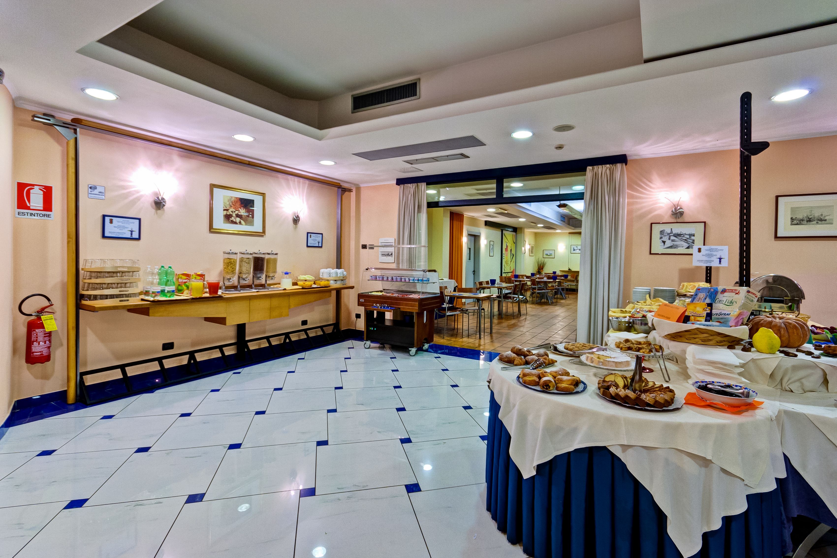A hotel dining area with a buffet setup, a fire extinguisher, and a ceiling vent.