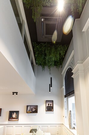 A modern interior with a high ceiling, recessed lighting, and a large window with a view. - Hotel Portinari (Bruges)