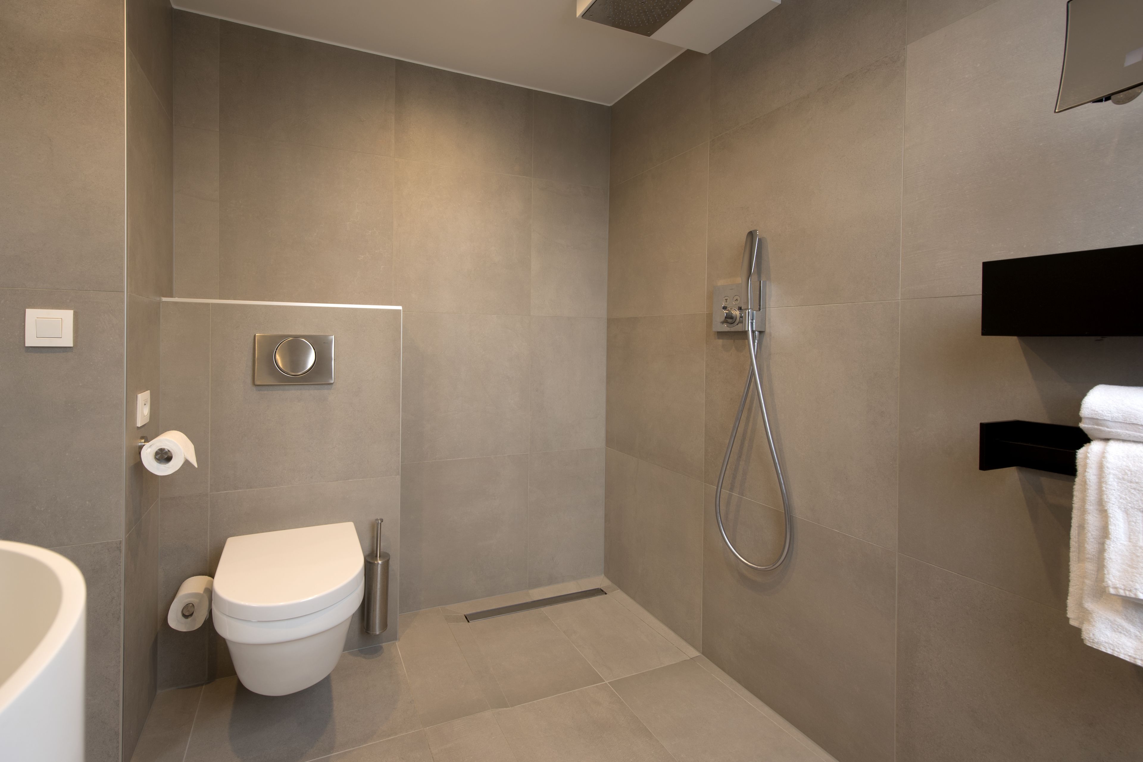 Un baño moderno con inodoro, ducha y perchero para toallas.
