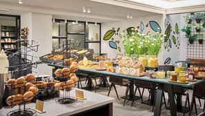 A breakfast buffet with various food items and a decorative wall with plant motifs. - Hotel Portinari (Bruges)