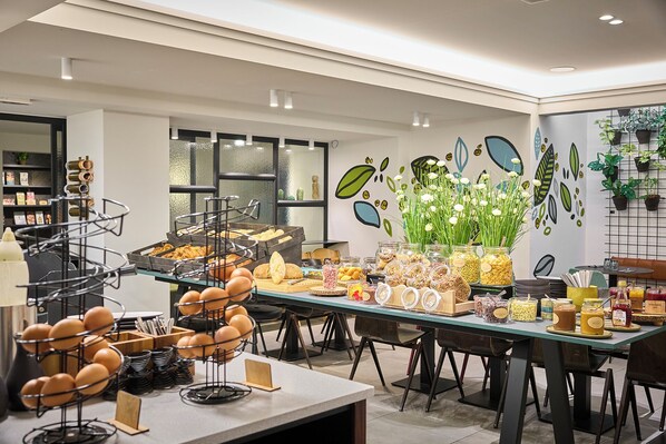 A breakfast buffet with various food items and a decorative wall with plant motifs.