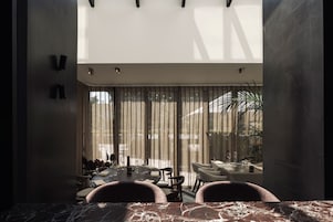 Un espace de repas moderne avec une table en marbre, des chaises et une vue dégagée grâce à de grandes fenêtres.