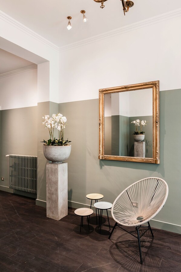 Un interior moderno con un espejo grande, una orquídea en maceta y una silla original.