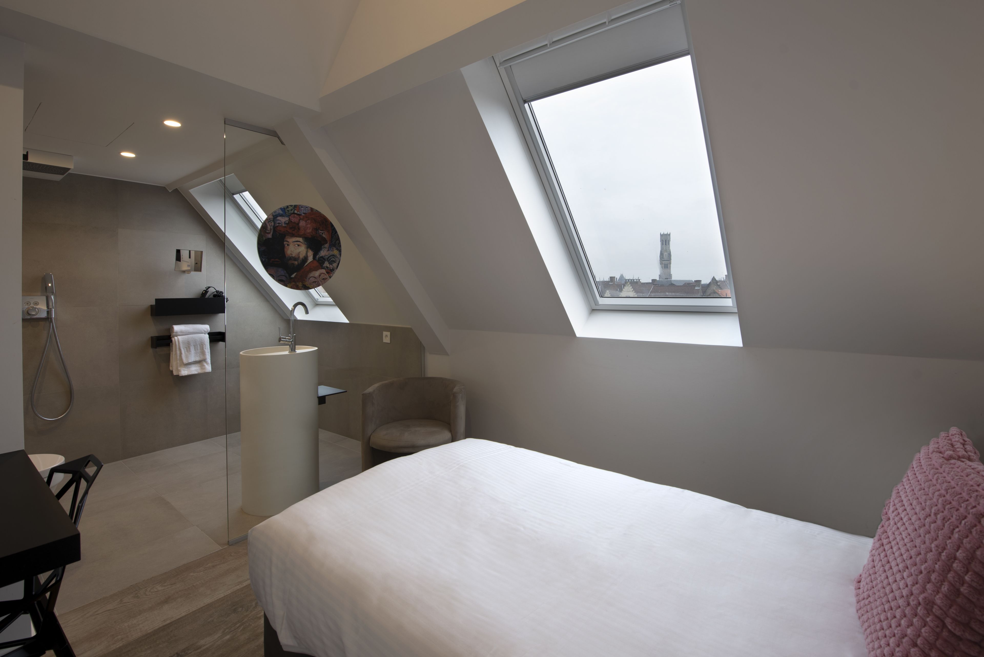 A modern bedroom with a skylight, a bed, a desk, and a chair.