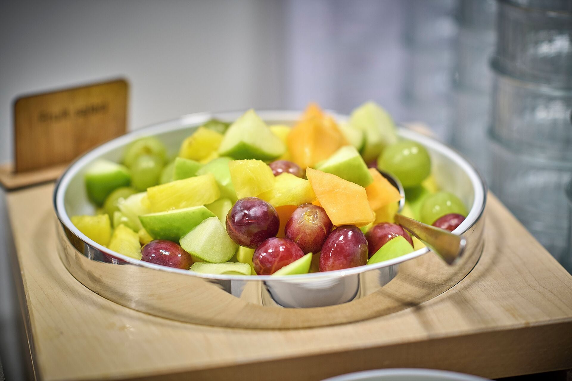 A bowl of assorted fruits on a wooden table.