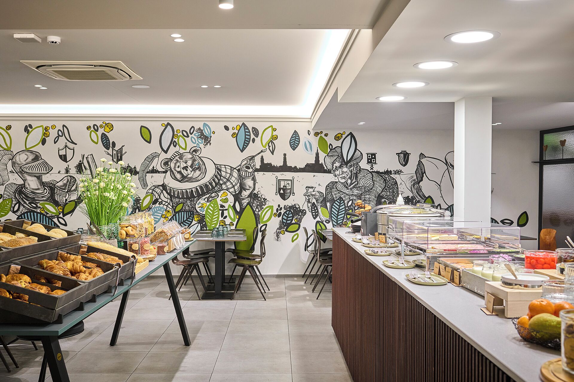 A buffet area with various food items and a mural on the wall.