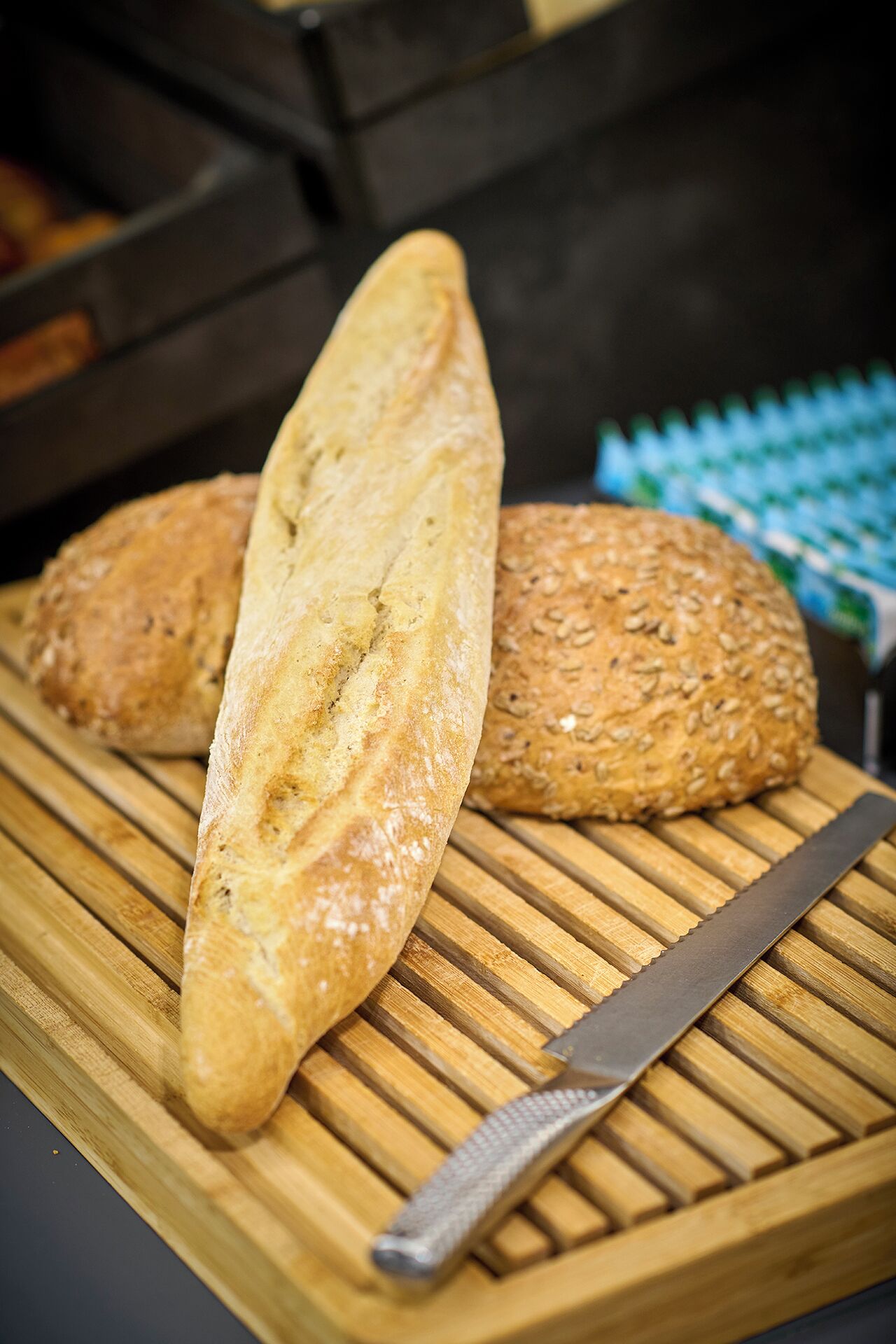 A wooden cutting board with two loaves of bread and a knife.