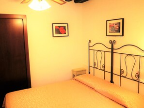 Un dormitorio con una cama, una puerta de madera y dos cuadros en la pared.