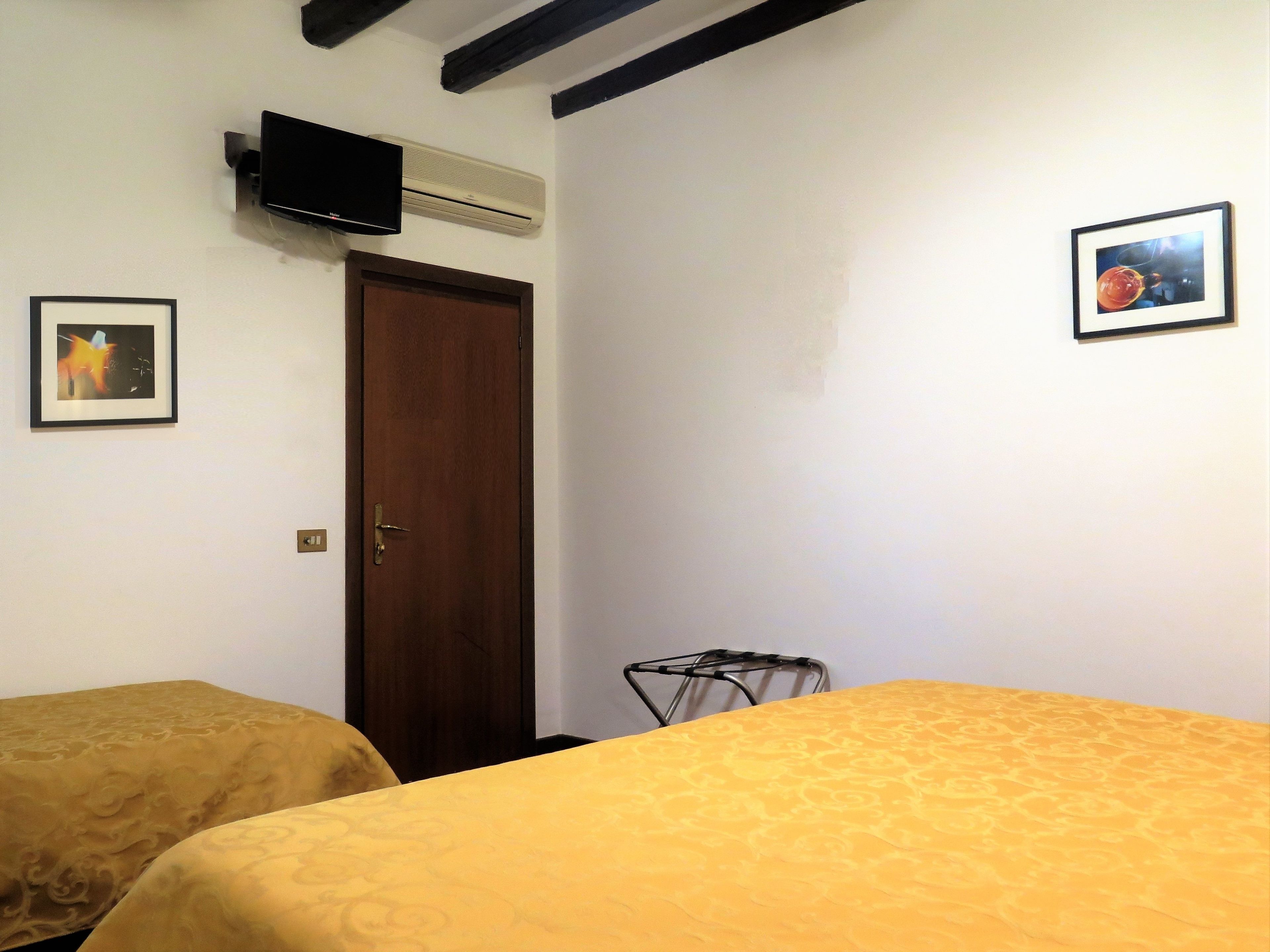 A room with two beds, a television mounted on the wall, and a door.