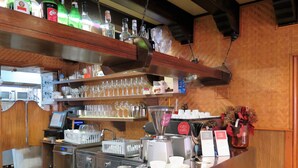 Un espace bar avec des étagères remplies de bouteilles d’alcool, de verres et un appareil à caf é.
