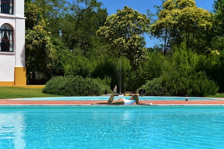 Una piscina al aire libre, sillones reclinables de piscina