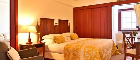 A hotel room with a bed, a desk, a chair, and a lamp.