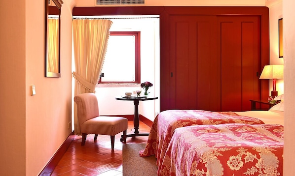 A hotel room with a bed, a chair, a small table with a vase, and a window with curtains. - Pousada Convento de Beja - Historic Hotel (Beja)