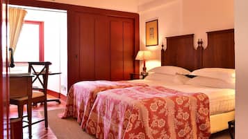 Una habitación de hotel con dos camas, un escritorio de madera, una silla, una lámpara y una puerta.