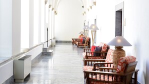 A corridor with arched ceilings, marble flooring, and furnished seating areas with lamps.