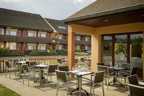 An outdoor patio with tables and chairs, a covered seating area, and a building in the background. - Hotel Campanile Gent (Ghent)