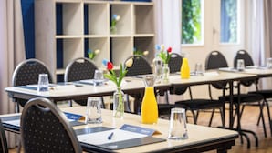 Une salle de conférence équipée de tables, de chaises et agrémentée de compositions florales.