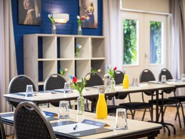 Una sala de conferencias con mesas, sillas y centros de mesa con flores.