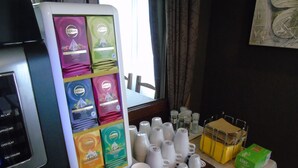 Una estación de bebidas con sabores de té Lipton, vasos desechables y una mesa con una caja de pañuelos.