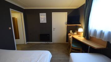 A hotel room with two beds, a desk with a chair, a television, and a window with curtains.