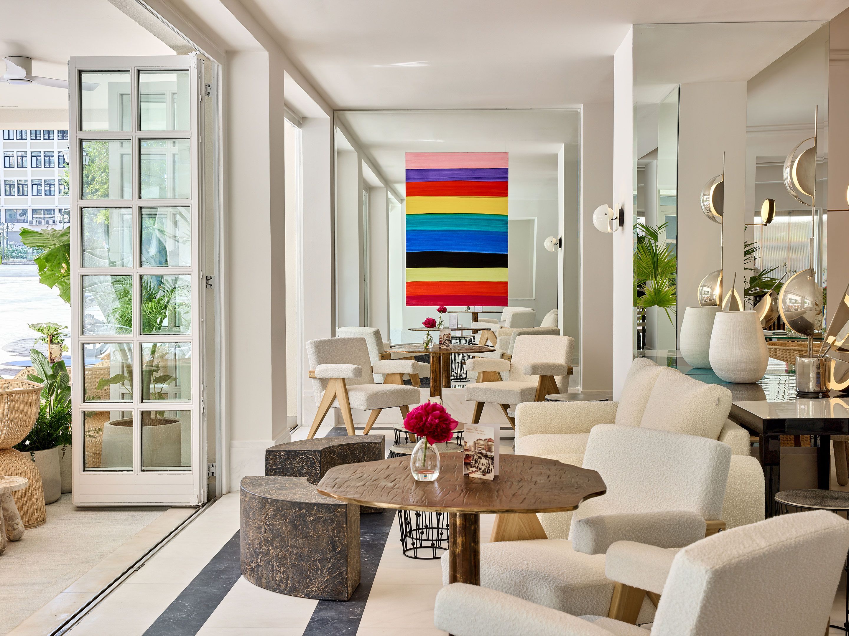 A modern interior with a large window, a central table with chairs, and a colorful abstract painting.