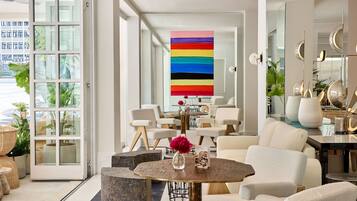 A modern interior with a large window, a central table with chairs, and a colorful abstract painting.