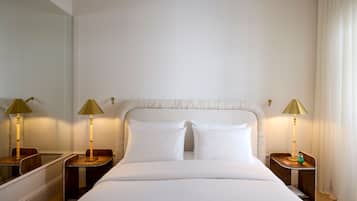 Een hotelkamer met een groot bed, twee nachtkastjes met lampen en een spiegel aan de muur.