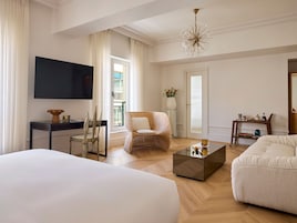 Una habitación de hotel moderna con una cama grande, un escritorio, una silla, una mesita de centro y un televisor montado en la pared.