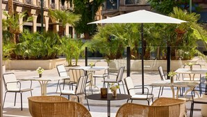 An outdoor seating area with wicker chairs, tables, and a white umbrella.