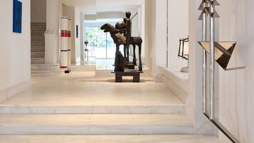 A hallway with marble flooring, a sculpture, and a staircase.