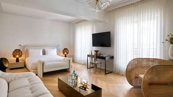 A modern hotel room with a bed, a desk, a television, a sofa, and a coffee table.