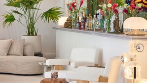 A modern living room with a sofa, chairs, a coffee table, a potted plant, and a shelf with decorative items. - ATHENA Pallas (Athens)