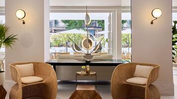 A modern interior with wicker chairs, a central table, and wall-mounted lights.