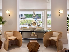Decoração moderna com cadeiras de vime, uma mesa central e luminárias fixadas na parede.