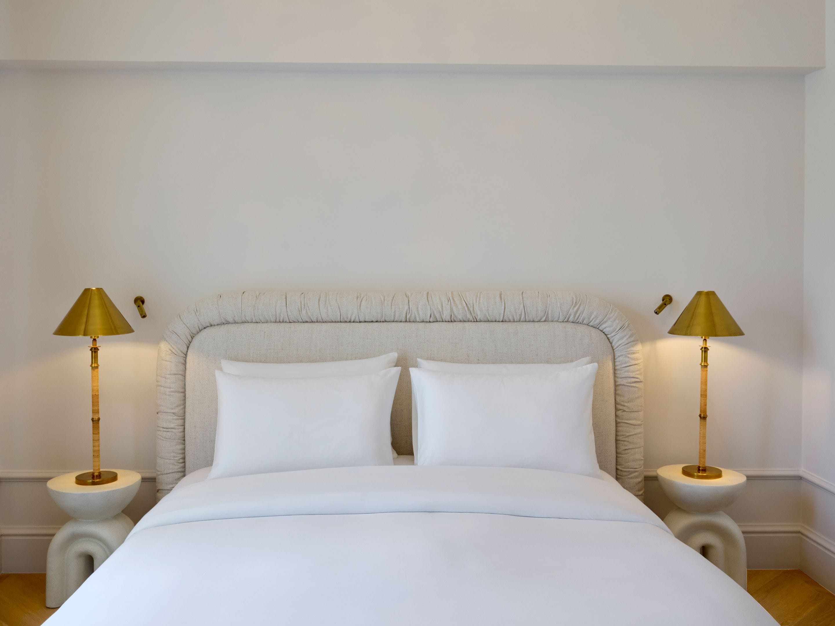A bed with white bedding, a tufted headboard, and two bedside lamps with gold shades.
