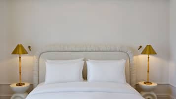 A bed with white bedding, a tufted headboard, and two bedside lamps with gold shades.