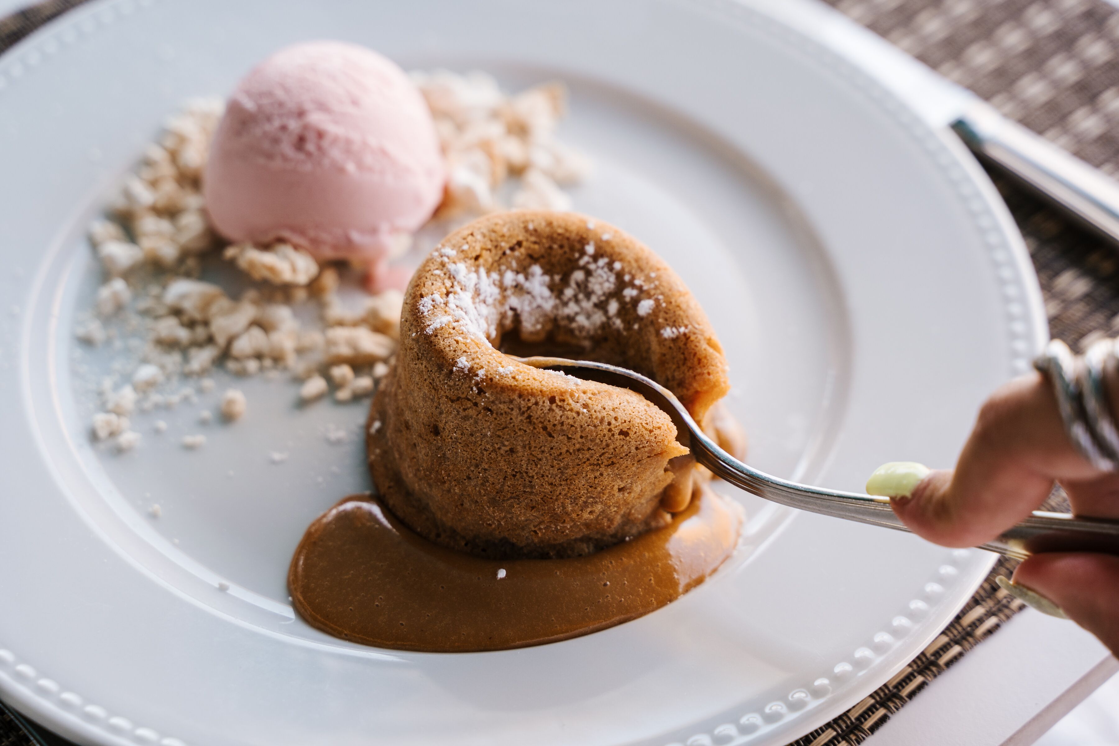 A dessert plate with a caramelized dessert, a scoop of ice cream, and a piece of cake.