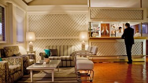 Un salon bien éclairé, doté d’un bar, de différents espaces pour s’asseoir et d’un mur décoré de motifs.
