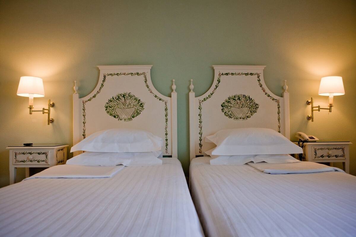 Une chambre double avec deux lits, chacun doté d’une tête de lit blanche et de deux tables de chevet assorties.