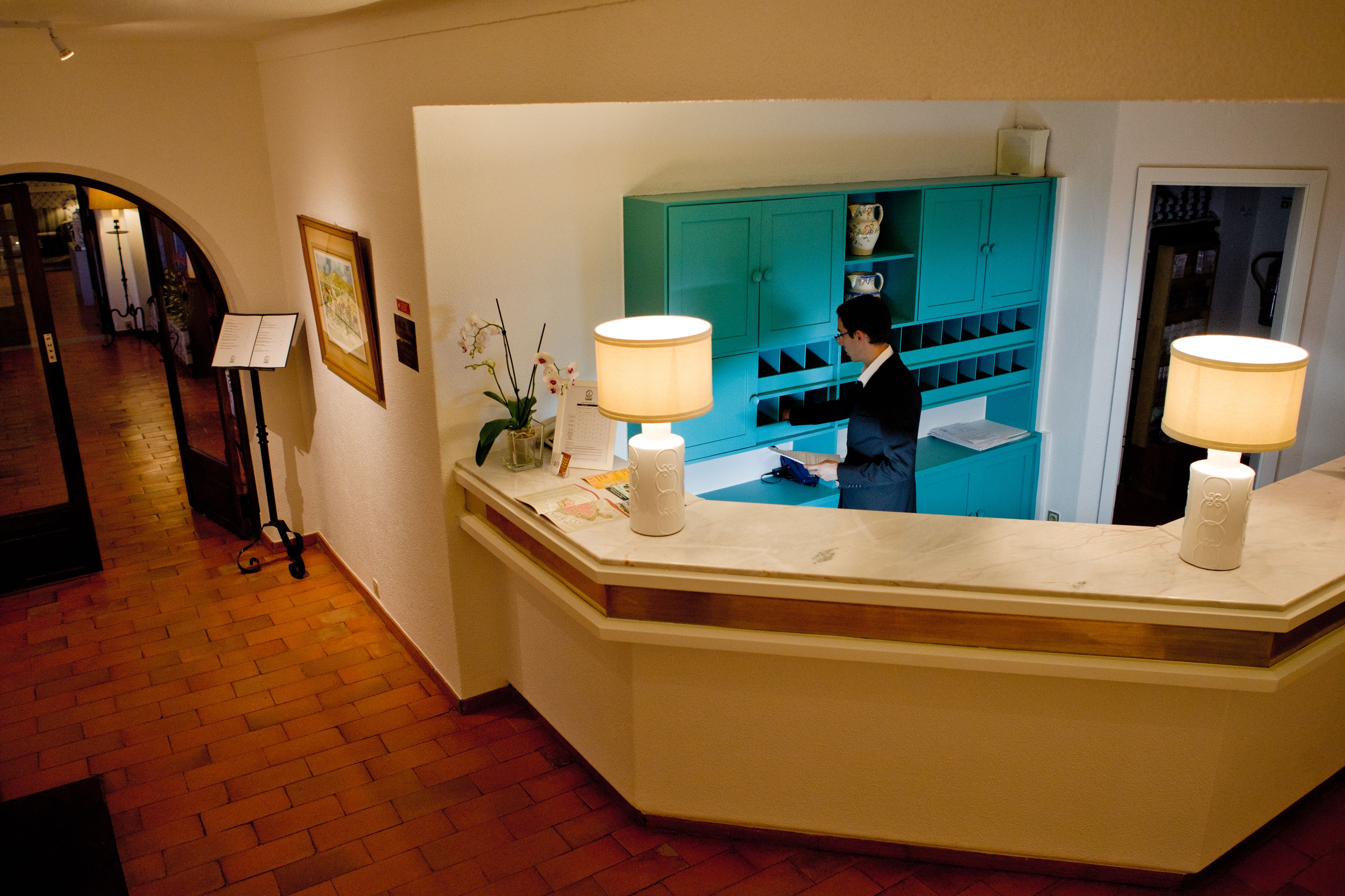 A reception desk with a teal-colored cabinet and two lamps.