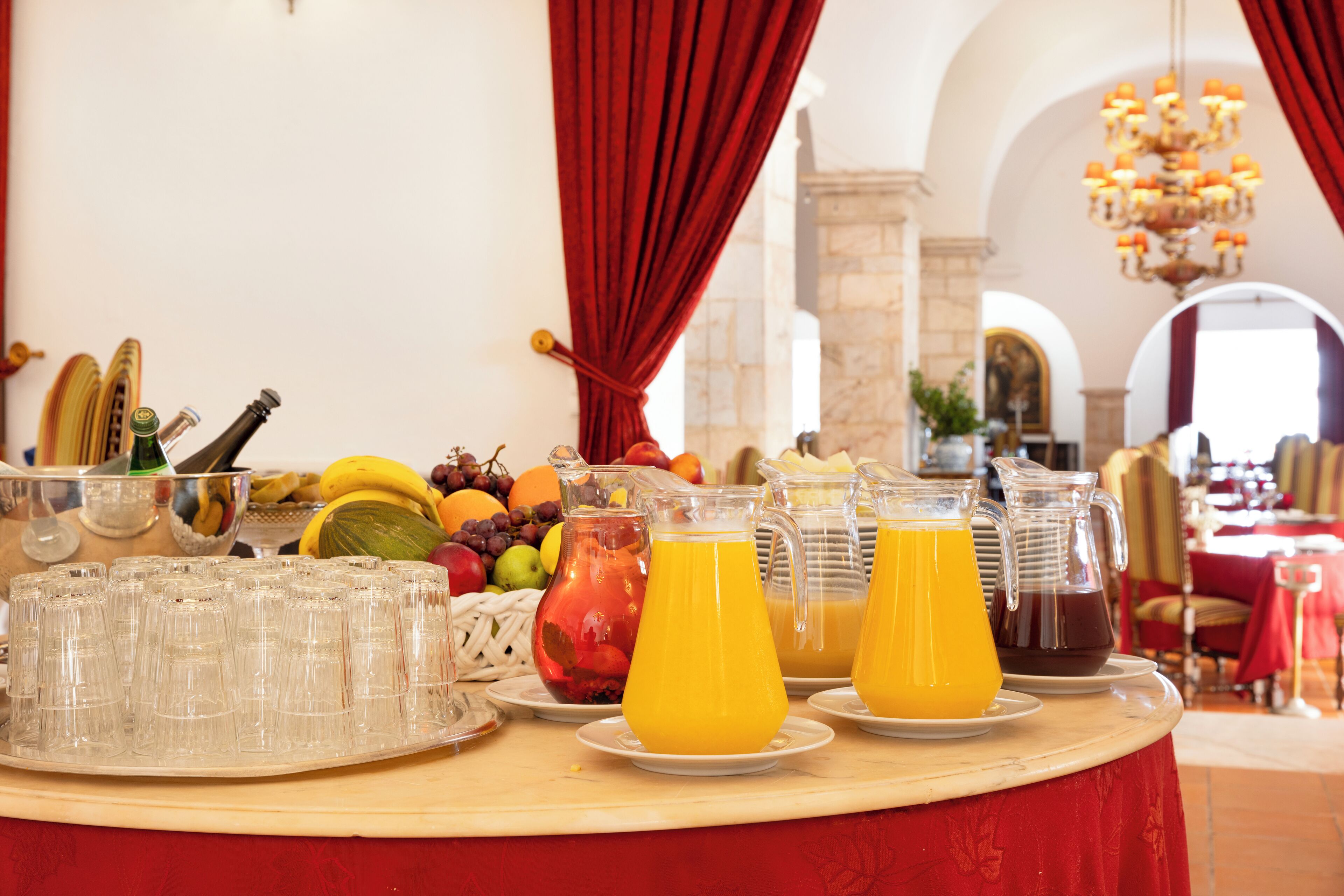 Un bufé de desayuno con diversas frutas, zumos y una botella de vino.