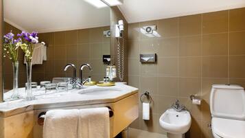 A modern bathroom with a large mirror, a sink with a vanity, a bidet, and a toilet.